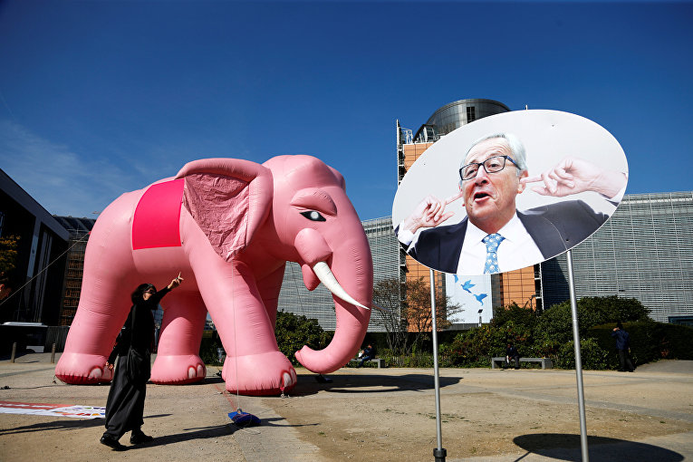 Надувной розовый слон рядом со знаком, изображающим президента Европейской комиссии Жана-Клода Юнкера. Перформанс организовали активисты-экологи перед штаб-квартирой Комиссии ЕС в Брюсселе, Бельгия.
