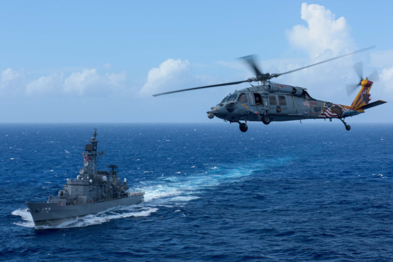 Морской ястреб ВВС США MH-60S летит над японским кораблем морской силы самообороны JS Shimakaze на юго-запад от Корейского полуострова.