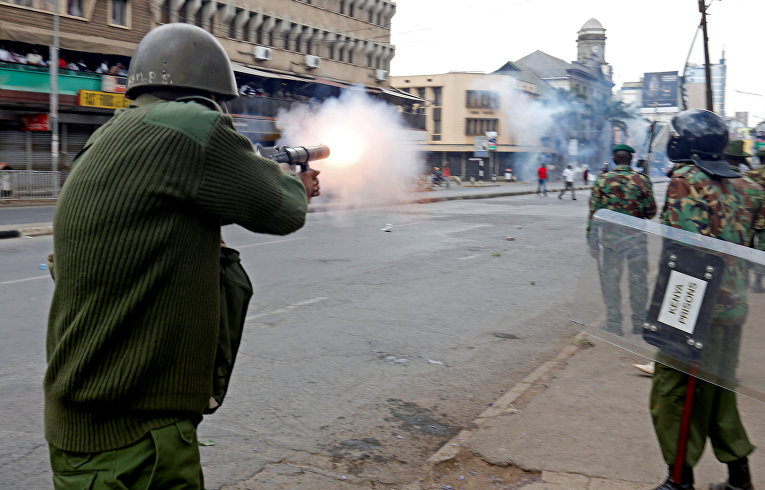 Омоновцы разжигают слезоточивый газ, разгоняя сторонников коалиции Национального суперсоюза Кении (НАСА) во время протеста на улице в Найроби.