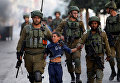 Израильские солдаты задерживают палестинского мальчика во время столкновений в городе Хеврон на Западном берегу.