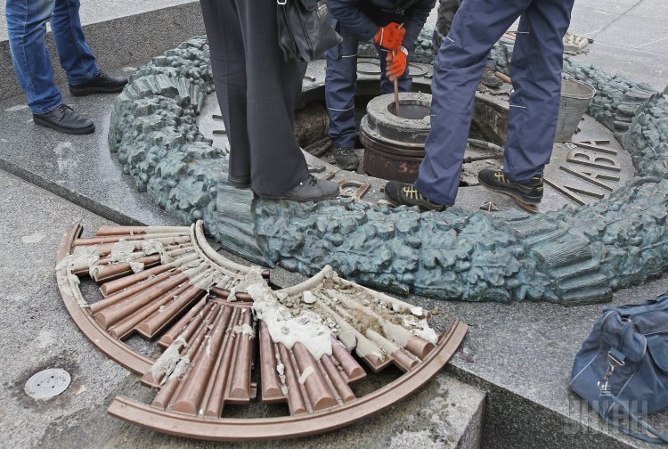 Коммунальщики очищают от цемента залитый Вечный Огонь в Киеве.