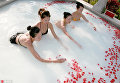 Женщины плавают в горячем источнике с добавлением молока и лепестков роз