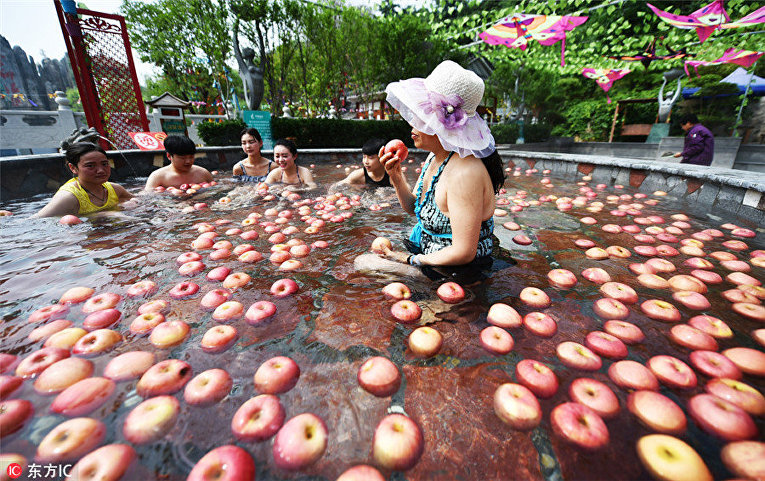 Женщина собирается съесть яблоко, плавающее в горячем источнике в Лояне