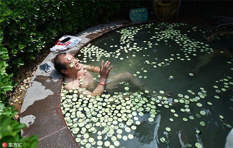 Мужчина наслаждается ванной с дольками огурца в  горячем источнике в Лояне