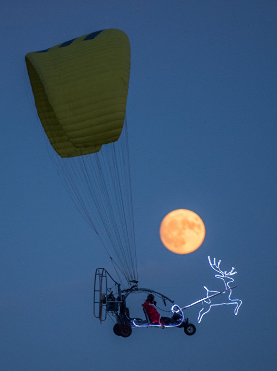 Человек в костюме Санта-Клауса, летит на фоне суперлуния,  Зиверсдорф, Германия
