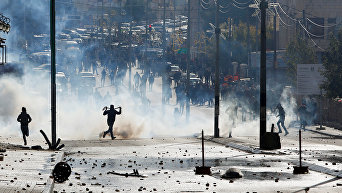 Палестинские протестующие бегут в укрытие от слезоточивого газа, во время столкновений израильскими войсками в знак протеста против решения президента США Дональда Трампа признать Иерусалим столицей Израиля в городе Вифлееме