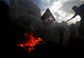 Палестинский протестующий готовится сжечь флаг США во время столкновений с израильскими войсками в знак протеста против решения президента США Дональда Трампа признать Иерусалим столицей Израиля, недалеко от еврейского поселения Бейт-Эль