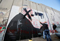 Палестинский человек перечеркивает стену, изображающую президента США Дональда Трампа, который нарисован на части израильского барьера, в городе Вифлеем на Западном берегу
