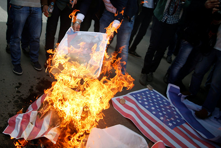 Палестинские демонстранты сжигают плакат с изображением президента США Дональда Трампа и флага США во время протеста против решения Трампа признать Иерусалим столицей Израиля в городе Газа