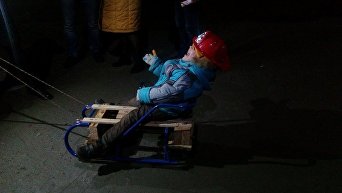 Ребенок катается на санках по асфальту в Мариуполе