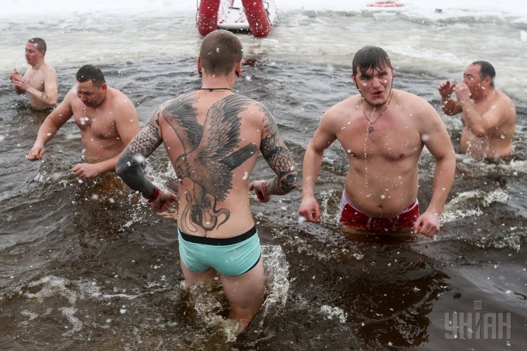 Люди купаются в проруби во время празднования Крещения Господня, возле Свято-Покровского собора, в Киеве, 19 января 2018 г