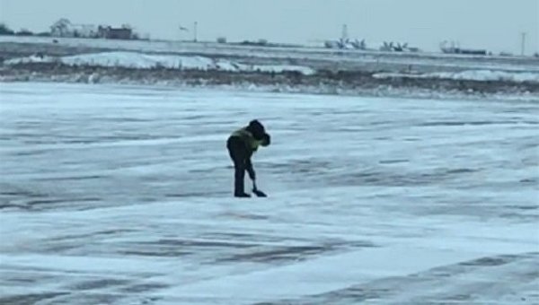 Сотрудник запорожского аэропорта чистит взлетную полосу от снега лопатой
