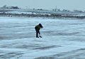 Сотрудник запорожского аэропорта чистит взлетную полосу от снега лопатой