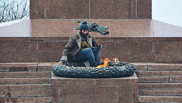 Бездомный греется на Вечном огне в Одессе