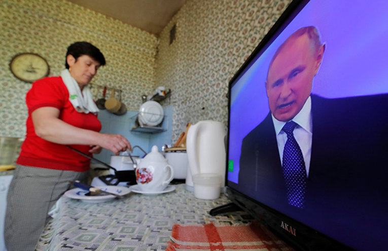 Жительница Москвы смотрит трансляцию церемонии инаугурации избранного президента России Владимира Путина