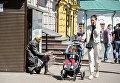 Молодая женщина с ребенком проходит мимо женщины, которая просит милостыню на центральной улице Киева