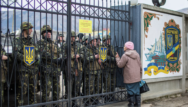 Местная жительница разговаривает с украинскими военными у ворот военной базы в селе Перевальное недалеко от Симферополя