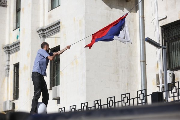 Активист срывает флаг РФ с посольства в Киеве