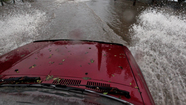 Автомобиль на залитой водой улице после ливня. Архивное фото