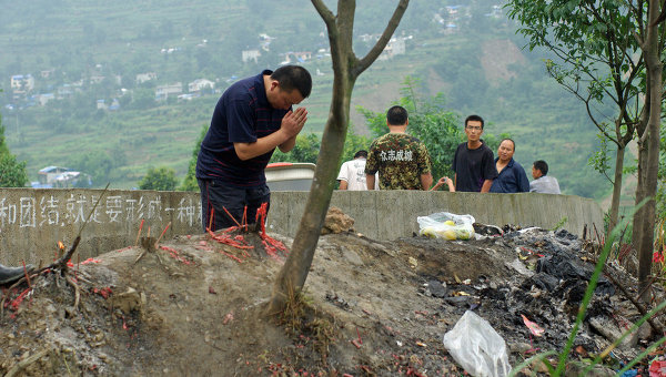 Мужчина молится после землетрясения в Китае