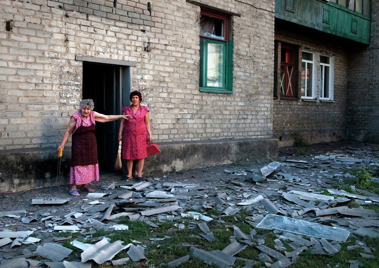 Местные жители стоят возле здания, где они живут, после обстрела в Донецке