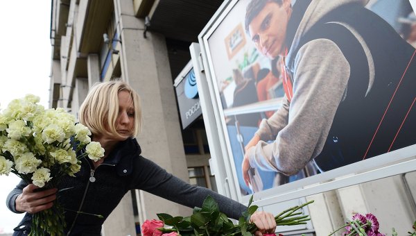 Коллега возлагает цветы в память о погибшем фотокорре Андрее Стенине