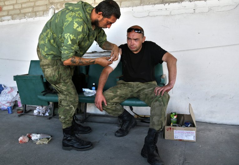Ополченец меняет повязку раненому в Старобешево
