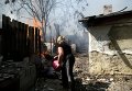 Местная жительница Донецка тушит пожар после обстрела