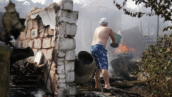 Местный житель Донецка тушит пожар после обстрела