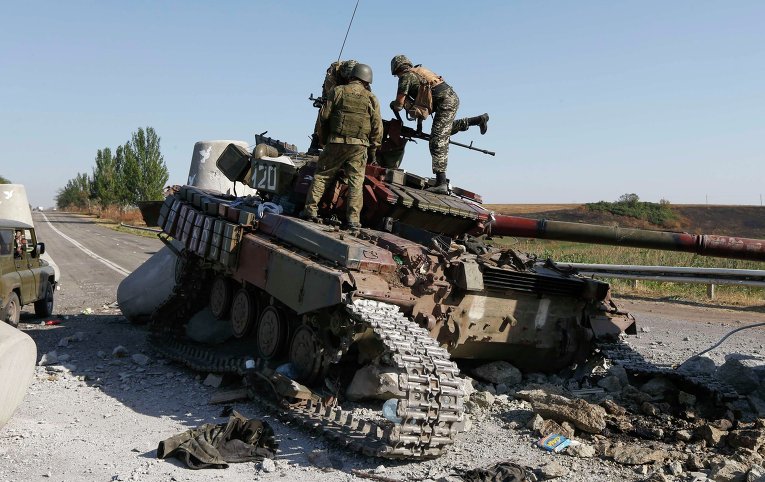 Украинские солдаты осматривают сожженный танк близ Мариуполя