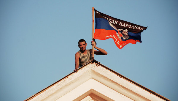 Ополченец устанавливает флаг ДНР. Архивное фото