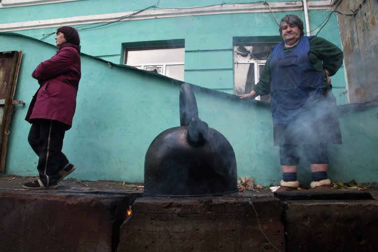 Люди кипятят воду недалеко от входа в бомбоубежище в Донецке