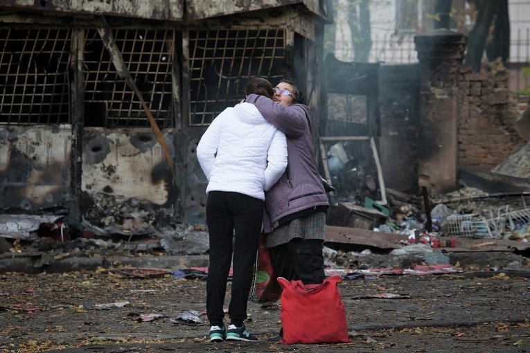 Женщины обнимаются недалеко от разрушенного магазина в Донецке