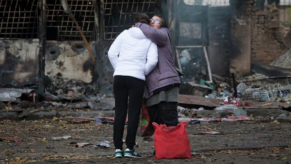 Женщины обнимаются недалеко от разрушенного магазина в Донецке