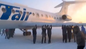 Пассажиры толкают самолет в аэропорту Игарки