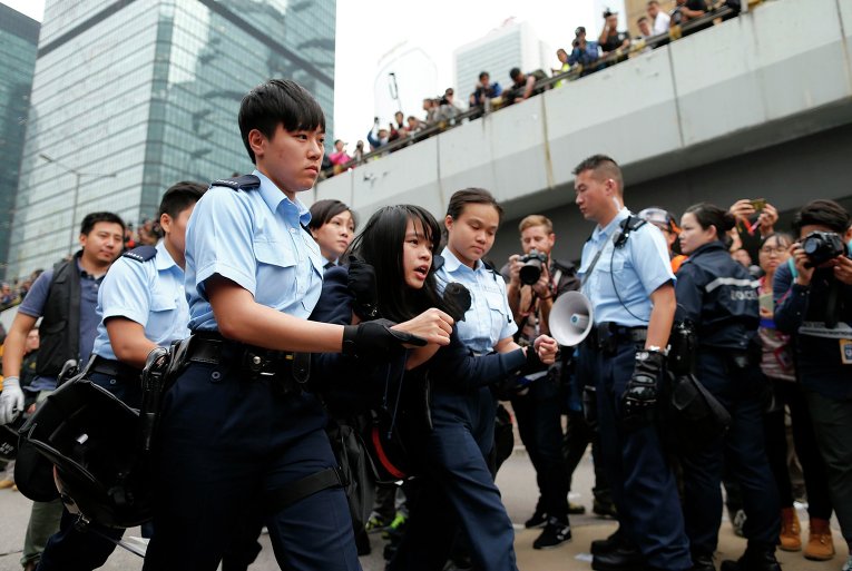 Операция по разбору баррикад в центре Гонконга. Полицейские задерживают протестующую