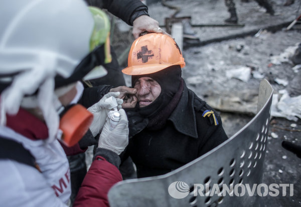 Протестующие оказывают медицинскую помощь мужчине, пострадавшему во время столкновений с сотрудниками правоохранительных органов у стадиона Динамо в Киеве.