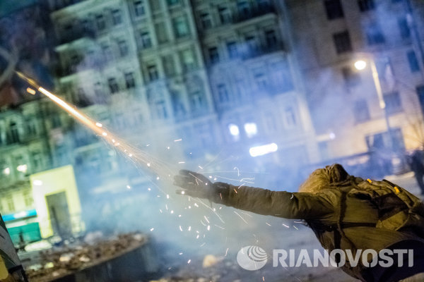 Участник массовых столкновений с сотрудниками правоохранительных органов пускает петарду в сторону полиции у стадиона Динамо в Киеве.