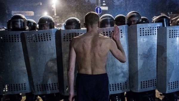 Участник акции протеста разговаривает с сотрудниками спецподразделения милиции Беркут на улице Грушевского в Киеве.