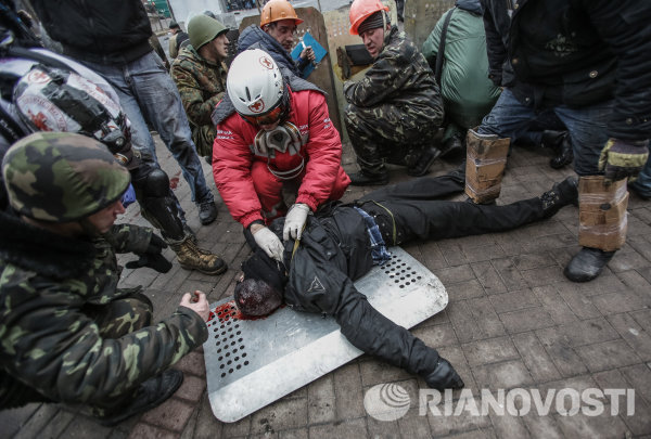 Сторонники оппозиции оказывают помощь раненому во время столкновений.