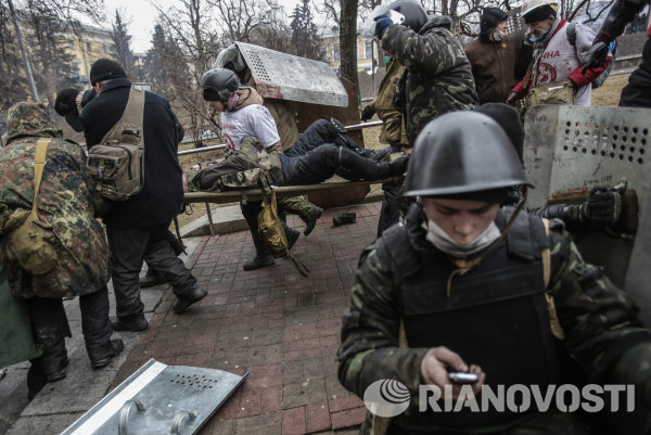 Сторонники оппозиции несут раненного во время столкновений на улице Институтской в Киеве.
