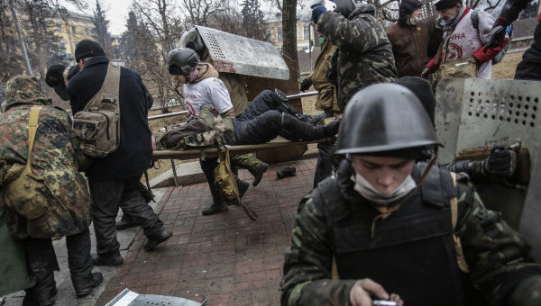 Сторонники оппозиции несут раненного во время столкновений на улице Институтской в Киеве.Архивное фото