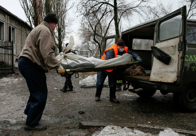 Мужчины загружают тело погибшего при обстреле в Донецке