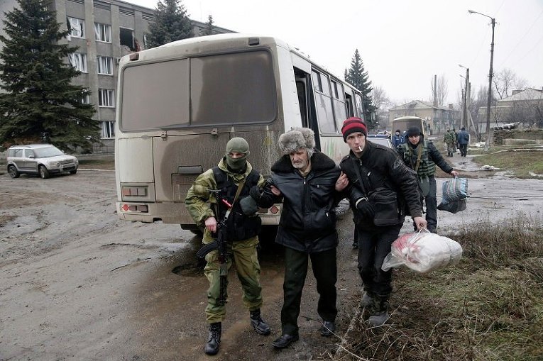 Украинский солдат помогает пожилому мужчине во время эвакуации жителей Дебальцево