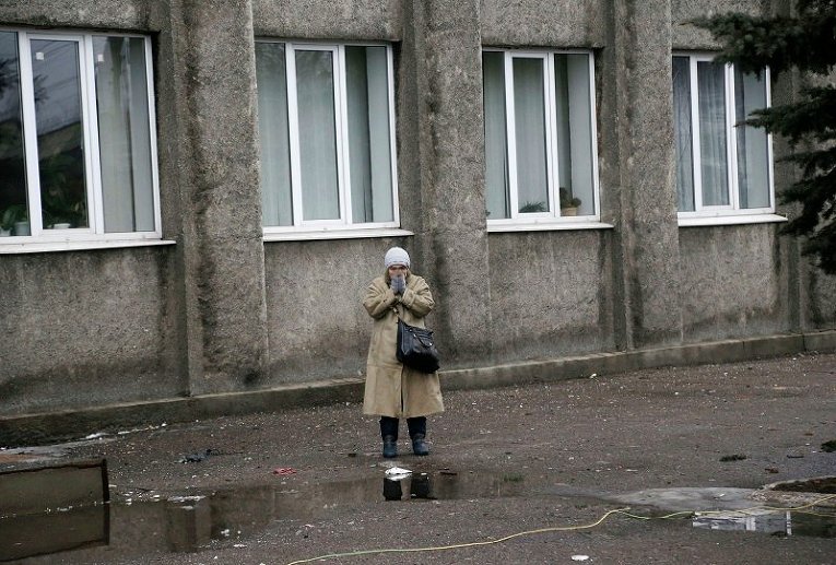 Женщина стоит возле обстрелянного здания администрации в Дебальцево