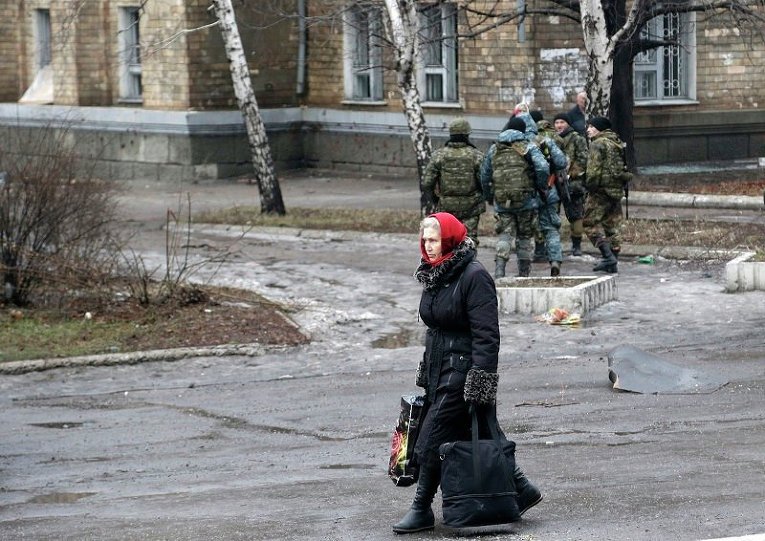 Жительница Дебальцево идет с сумками в автобус, на котором эвакуируют горожан