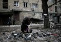 Пожилая женщина кормит голубей возле своего разрушенного дома в Дебальцево