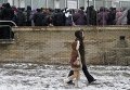 Женщина с ребенком идут мимо очереди за гуманитарной помощью в Донецке