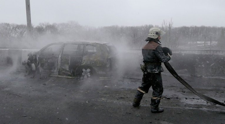 Пожарный на месте обстрела в Донецке тушит сгоревший автомобиль