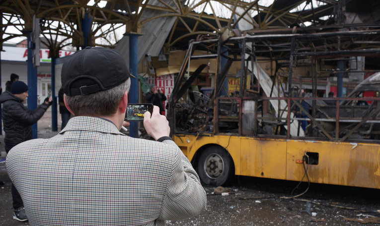Местный житель фотографирует сгоревший автобус на автовокзале в Донецке